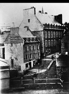 an old black and white photo of some buildings with stairs leading up to the top