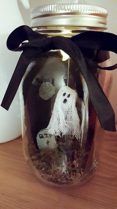 a glass jar filled with halloween decorations on top of a wooden table