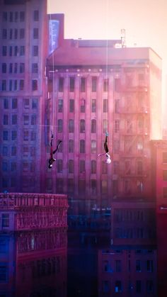 two people are performing aerial tricks in front of tall buildings on a city street at sunset