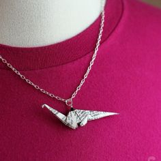 an origami bird necklace is displayed on a mannequin