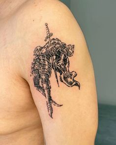 an elephant tattoo on the left shoulder and chest, with a cross in its trunk