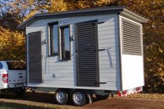 a tiny house on the back of a truck in front of some trees and grass