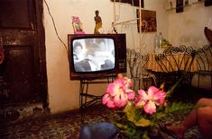 a small television sitting on top of a table next to a vase with flowers in it