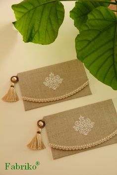 two pieces of cloth with tassels on them sitting next to a green plant