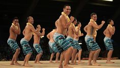 a group of men standing on top of a wooden floor wearing blue and green trunks