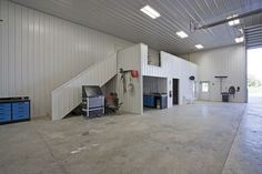 an empty garage with stairs and workbench in the center, on concrete flooring