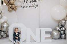 a baby is sitting in the middle of a one - year birthday photo with balloons