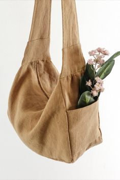 a brown bag with flowers in it hanging from the side on a white wall background