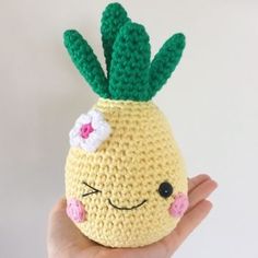 a crocheted pineapple with a flower on it's head is held up