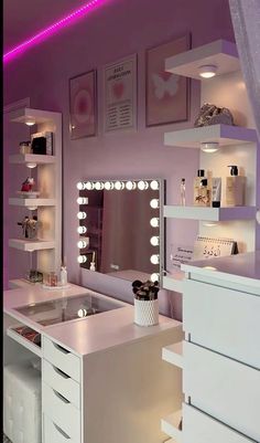 a white vanity with lights and drawers in a pink room that is lit up at night