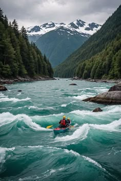 a person in a kayak on a river with mountains in the backgroud