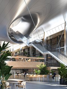 the interior of an office building with plants and tables in front of stairs leading up to two levels