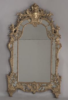 an ornate gold framed mirror against a gray wall