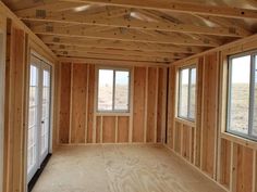 an empty room with wooden walls and windows