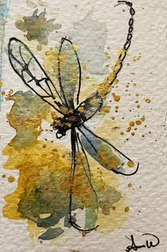 a drawing of a dragonfly sitting on top of a piece of paper with watercolor paint