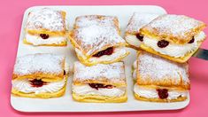 several pastries are arranged on a white tray with powdered sugar and jelly toppings