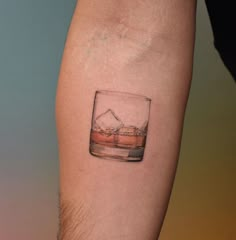 a small glass tattoo on the left forearm and arm, with an ice cube in it