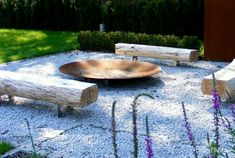 two wooden benches sitting next to each other on top of a gravel covered ground with purple flowers