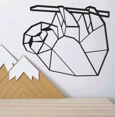 a paper cut out of the shape of a sloth hanging on a wall with mountains in the background