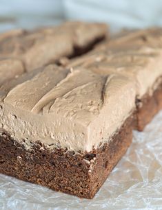 two brownies with frosting sitting on top of plastic wrap