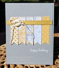 a happy birthday card with yellow and gray ribbons on it, sitting on a wicker basket