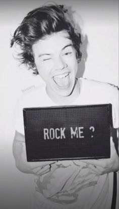 a young boy holding up a sign with the words rock me? on it in front of his face