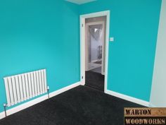 an empty room with blue walls and black carpeted flooring in the center is a white radiator