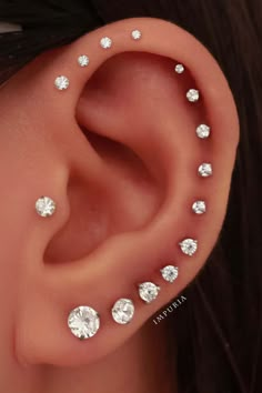 a woman's ear is adorned with small white diamond studs