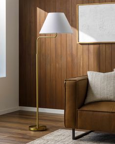 a living room with wood paneling and a lamp on the floor next to a couch