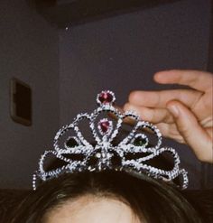 a close up of a person holding a tiara over their head with both hands