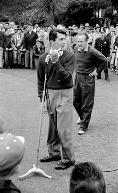 an old black and white photo of a man holding a golf club in front of a crowd