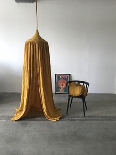 a room with a chair and a yellow drape hanging from the ceiling next to a painting