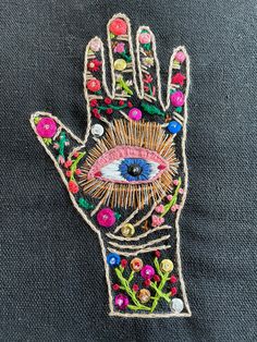 a hand with an eye on it is embroidered onto the back of a black jacket