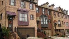 a row of brick townhouses with garages and stairs leading up to the front door