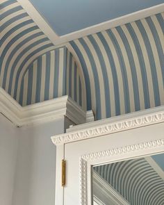 the ceiling is painted with blue and white striped wallpaper, along with a mirror