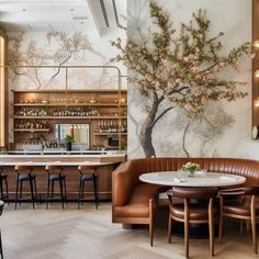 a restaurant with tables, chairs and a tree painted on the wall behind it's bar