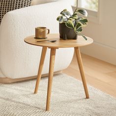 a wooden table with a potted plant on it next to a white couch in a living room