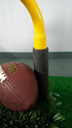 a football sitting on top of a lush green field next to a yellow tee ball