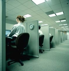 a woman sitting at a desk in an office cubicle