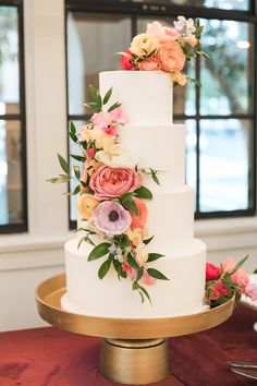 a three tiered white cake with pink and yellow flowers