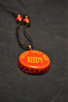 a bottle cap necklace with the words red's on it is laying on a black surface