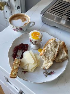 a plate with bread, jam and butter on it next to a cup of coffee