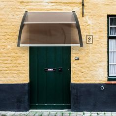 a green door and window in front of a yellow building with two windows on each side