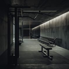 an empty bench sits in the middle of a dark room with concrete walls and flooring