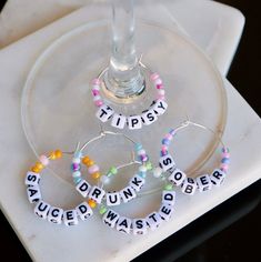 three wine glasses sitting next to each other on top of a white plate with beads