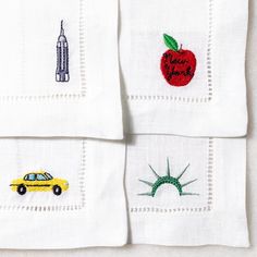 four napkins with embroidered images of cars, buildings and trees on them are shown