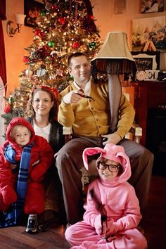 a man and two children sitting in front of a christmas tree with an adult standing next to them