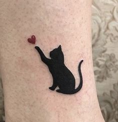 a black cat with a red heart on its leg