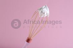 a whisk on a pink background with white cloth