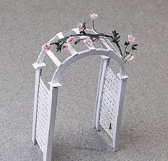 a small white arch with pink flowers on it